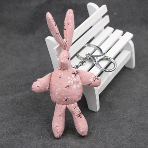 Porte-clés lapin en tissu floral rose avec fermoir mousqueton argenté sur banc