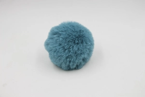 Close-up of soft blue-green faux rabbit fur pompom charm with fluffy plush texture