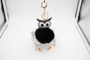 Détail d'un porte-clés chouette en pompon avec fermoir doré sur un mini banc blanc