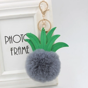 Macro detail of pineapple keychain with grey faux fur pompom and green PU leather leaves