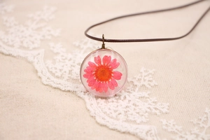 Détail macro du collier pendentif fleur séchée rose avec fil de bronze fait à la main