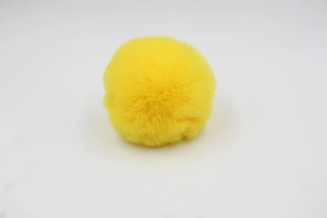 Macro detail of a fluffy bright yellow 8cm faux rabbit fur pom pom for bags and accessories