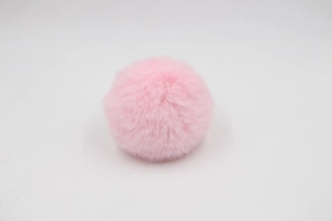 Close-up of a fluffy pink faux rabbit fur pompom charm for bags and keychains