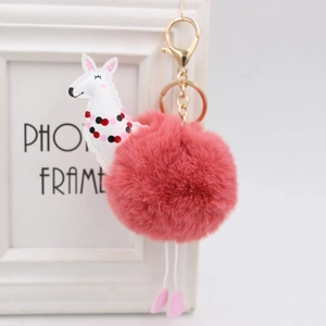 Dettaglio di un portachiavi con pompon rosa morbido e ciondolo alpaca con gancio oro