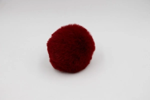 Close-up of a 8cm dark red faux rabbit fur pom-pom ball for bags and DIY craft accessories
