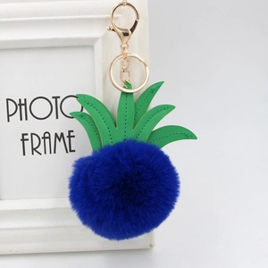 Detailed shot of dark blue pineapple fur pompom keychain with green faux leather leaves