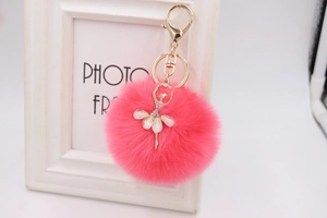 Detail of rose red faux fur pompom keychain with a rhinestone ballerina pendant