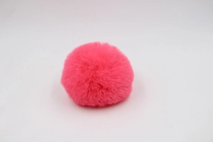 Detail showing the soft texture and round shape of a pink faux fur 8cm pom-pom keychain