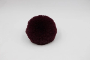 Close-up of fluffy burgundy faux rabbit fur pom pom with dense and soft texture detail
