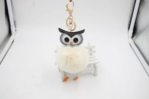 Vue détaillée du porte-clés hibou avec anneau doré sur un petit banc décoratif