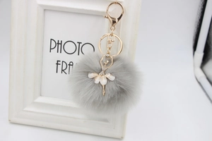 Detail of grey fluffy faux fur ball keychain with rhinestone ballet dancer charm