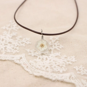 Vue rapprochée du collier artisanal avec fleur blanche séchée en pendentif résine