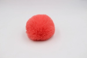 Detail of coral red faux rabbit fur pom pom showing soft fluffy texture for bag charms