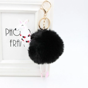 Dettaglio di un portachiavi a pompon nero con un ciondolo a forma di alpaca in pelle