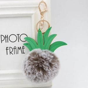 Close-up of fluffy pineapple pom-pom keychain with green leaves and gold metal hook