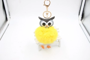 Vue détaillée d'un porte-clés hibou en fourrure jaune avec fermoir doré sur chaise