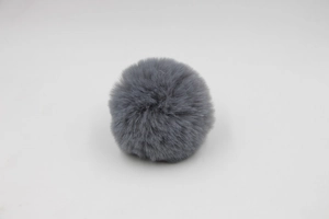 Detail of dark grey faux fur pompom showing soft synthetic fiber texture and round shape