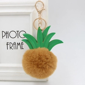 Detail view of pineapple keychain with green leather leaves and soft brown fur pompom