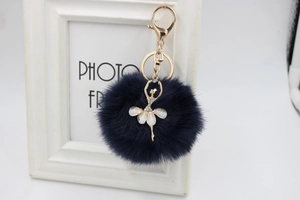 Detailed view of ballet dancer keychain with navy blue plush ball and golden hook