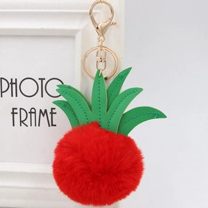 Close-up of red pineapple plush keychain with green leather leaves and gold clasp