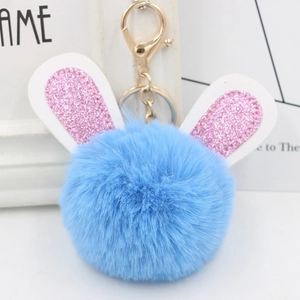 Light blue faux fur pompom keychain with pink glitter bunny ears and golden metal clasp
