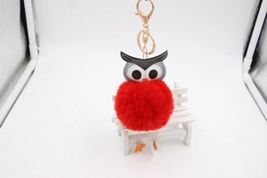 Détail d'un porte-clés hibou en fausse fourrure rouge avec anneau en métal doré