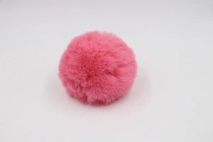 Close-up of a soft pink faux rabbit fur pom pom with fluffy texture for bags and accessories
