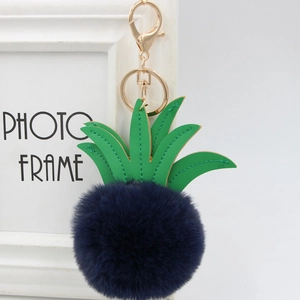 Close-up of blue pineapple faux fur keychain with green leather leaf and gold metal clip