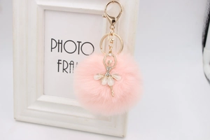 Detailed view of pink faux fur pompom keychain with crystal rhinestone ballerina pendant