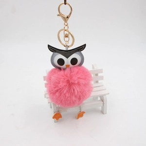 Gros plan d'un porte-clés chouette rose en peluche avec fermoir doré sur un banc miniature