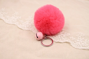 Detail of fluffy rose red faux fur pompom keychain with pink bell and silver ring