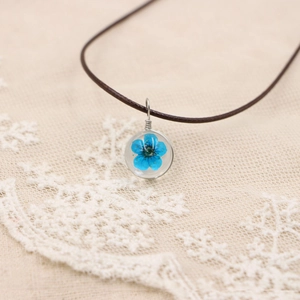 Collier artisanal avec véritable fleur séchée bleue en pendentif résine et cordon cuir
