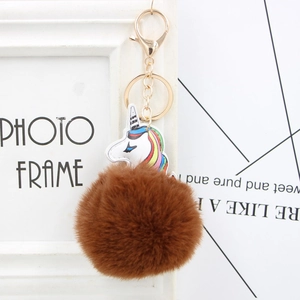 Detail of colorful unicorn leather charm with fluffy brown fur pompom and gold keychain