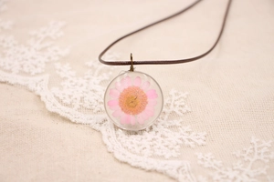 Vue détaillée du pendentif en résine fait main avec marguerite rose et cordon brun