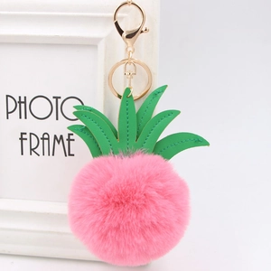 Close-up of pink fur pompom pineapple keychain with green leather leaves and gold clasp