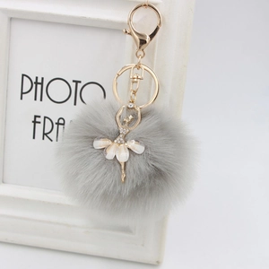Close-up of fluffy grey faux fur pompom keychain with a rhinestone ballet dancer charm