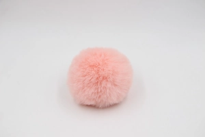 Close-up of fluffy 8cm light pink faux rabbit fur pom pom for bags and hats