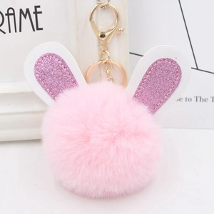 Close-up of pink faux fur pompom keychain with sequin bunny ears and golden clasp