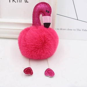 Detail of sequin flamingo plush keychain with rose red faux fur ball on white desk