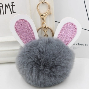 Detail of plush grey bunny ears pom-pom keychain with shimmering pink glitter accents