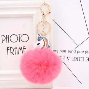 Detail of soft rose pink faux fur pom pom with colorful unicorn bag charm and gold clasp