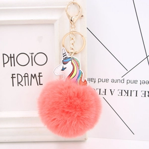 Close-up of fluffy coral pink pompom keychain with golden clasp and unicorn detail