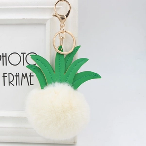 Detail of pineapple faux fur pompom keychain with green leather leaves and gold clasp
