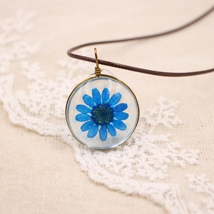 Vue macro du collier marguerite bleue séchée avec enroulement en fil de bronze