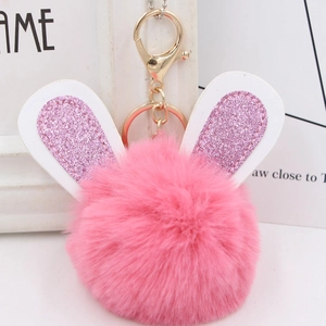 Detailed close-up of pink fluffy pompom keychain with glittering bunny ears and gold ring