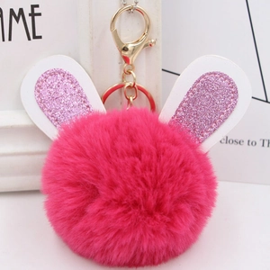 Close-up of fluffy pink pom-pom keychain with sequined bunny ears and golden hardware