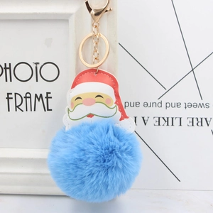 Close-up of bright blue pompom keychain with Santa Claus leather charm and golden clasp