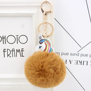 Macro shot of a fluffy brown faux fur unicorn pompom keychain with golden metal clasp