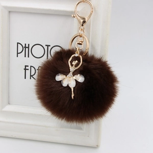 Close-up of a brown faux fur ball keychain with a golden rhinestone ballerina pendant