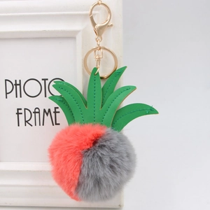 Close-up of pink and grey faux fur pineapple keychain with green leather leaves and gold clasp